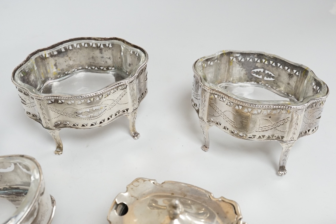 A pair of George III pierced silver shaped oval salts by Hester Bateman, London, 1783 (a.f.), with clear glass liners, together with one other George III silver oval salt, London, 1783 and two later silver mustard pots.